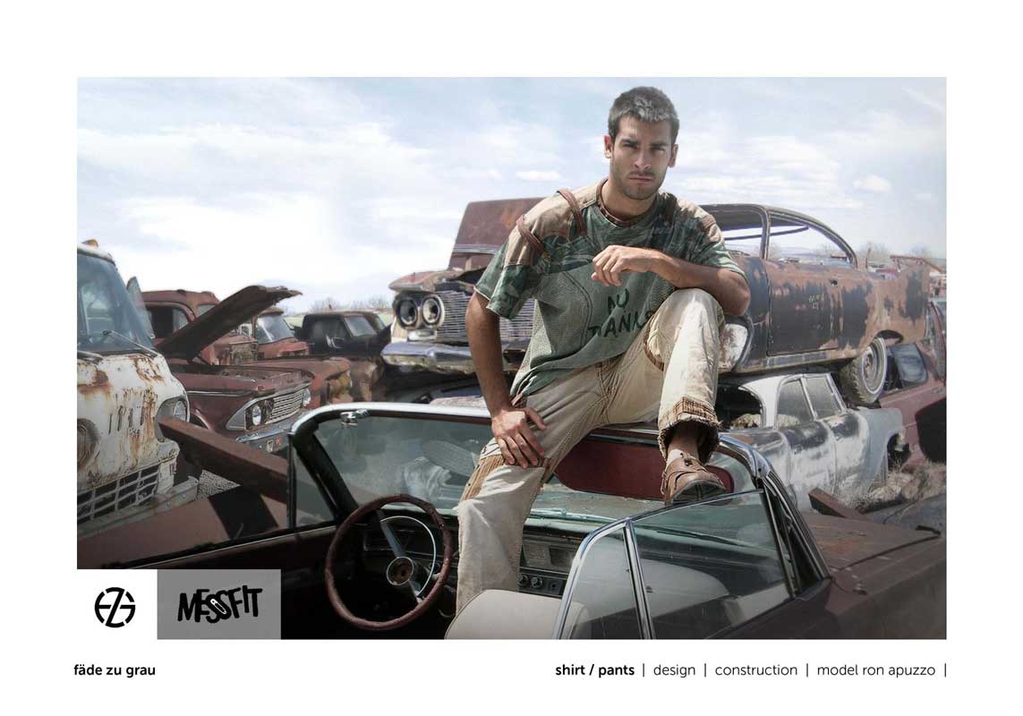 male fashion model in a junk yard presents green shirt and light brown pants